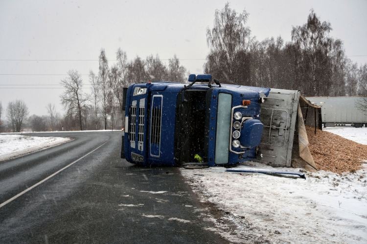 A truck lies overturned on a snowy road in Riverside, California